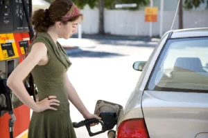 girl at the gas station filling up the fuel tank in her gas efficient car